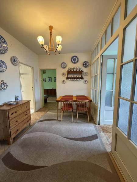 Novinka: Priestranný svetlý byt s balkónmi pri Kuchajde. Vajnorská - Jedáleň v 3-izbovom byte s dreveným dekorom, koberec, stôl a dekoratívne taniere.