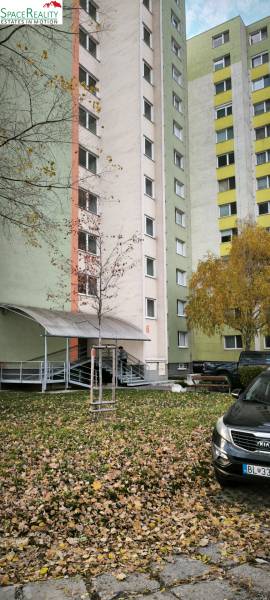 Prenajmeme 3 izb  byt na Korytnickej ulici - Panelový bytový dom na Korytnickej ulici, Bratislava - Podunajské Biskupice, obklopený zeleňou.