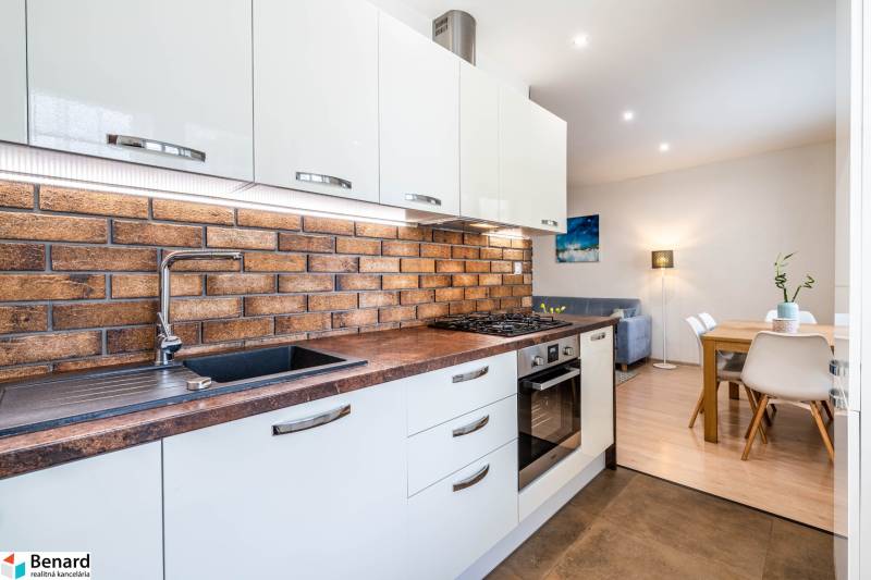 Na prenájom štýlový  3 - izb. byt  (Košice - Sever) - Kuchyňa v 3-izbovom byte s tehlovým obkladom na stene a podlahou s dreveným dekorom.