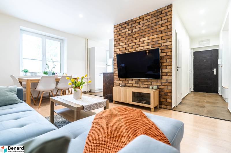 Na prenájom štýlový  3 - izb. byt  (Košice - Sever) - Obývacia izba s pohovkou, stolom a TV, v 3-izbovom byte. Podlaha s dreveným dekorom.