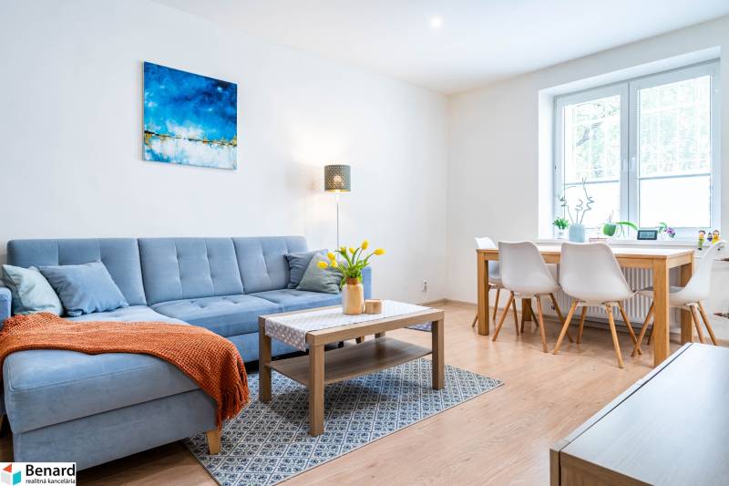 Na prenájom štýlový  3 - izb. byt  (Košice - Sever) - Obývacia izba v 3-izbovom byte so sedačkou a jedálenským stolom, podlaha s dreveným dekorom.