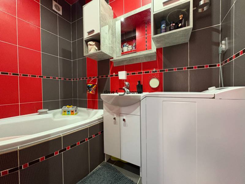 Na predaj: Investičný 3 izb.byt + murovaná PIVNICA - Kúpeľňa v 3-izbovom byte s červenými a sivými obkladmi, vaňou a práčkou.