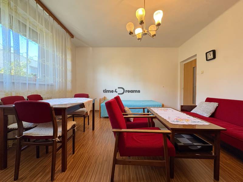 Na predaj: Rodinný dom v meste Levice - Obývacia izba v rodinnom dome s červeným nábytkom a podlahou s dreveným dekorom.