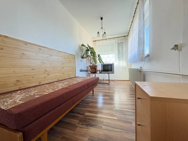 Na predaj: Rodinný dom v meste Levice - Izba v rodinnom dome s posteľou, televíziou a podlahou s dreveným dekorom.