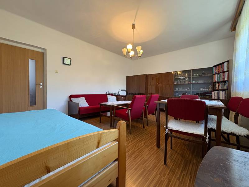 Na predaj: Rodinný dom v meste Levice - Obývacia izba v rodinnom dome s podlahou s dreveným dekorom, červeným nábytkom a knižnicou.