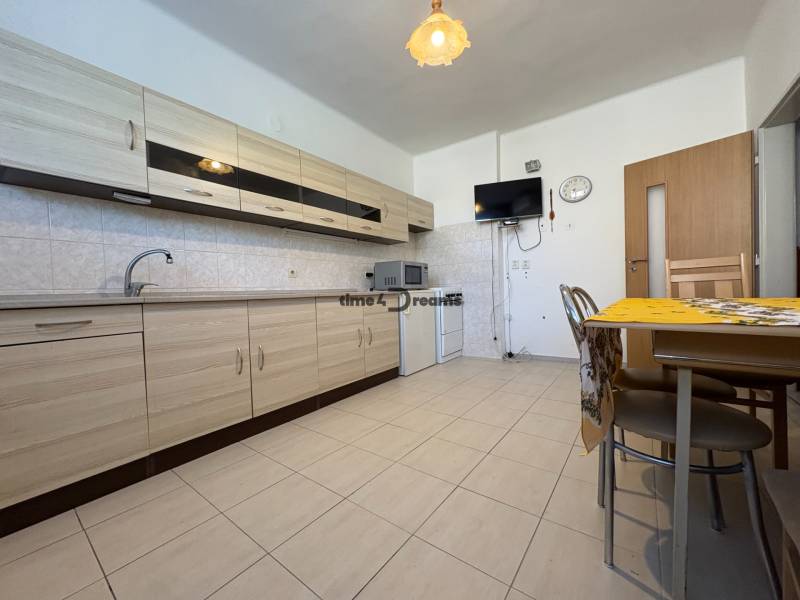 Na predaj: Rodinný dom v meste Levice - Kuchyňa v rodinnom dome s krémovými skrinkami, jedálenským stolom a nenápadným dekorom.