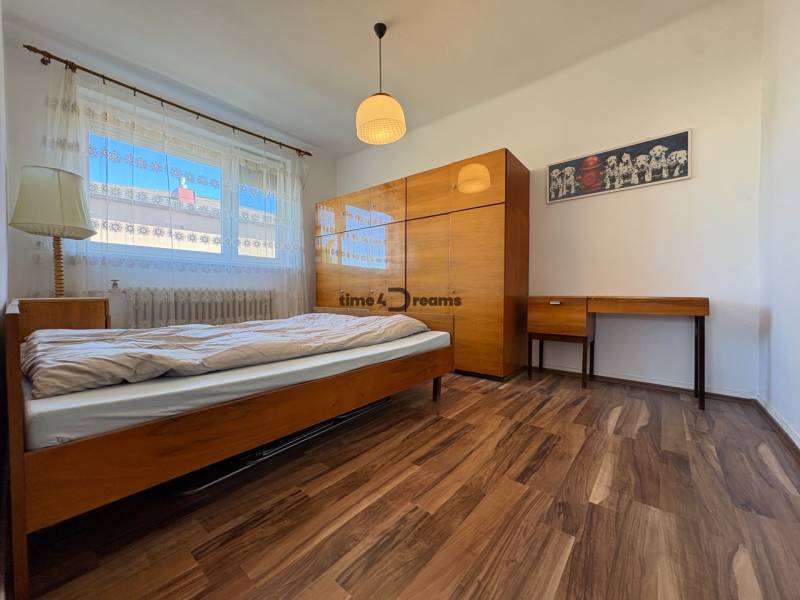 Na predaj: Rodinný dom v meste Levice - Spálňa s podlahou s dreveným dekorom, posteľou a nábytkom v rodinnom dome.