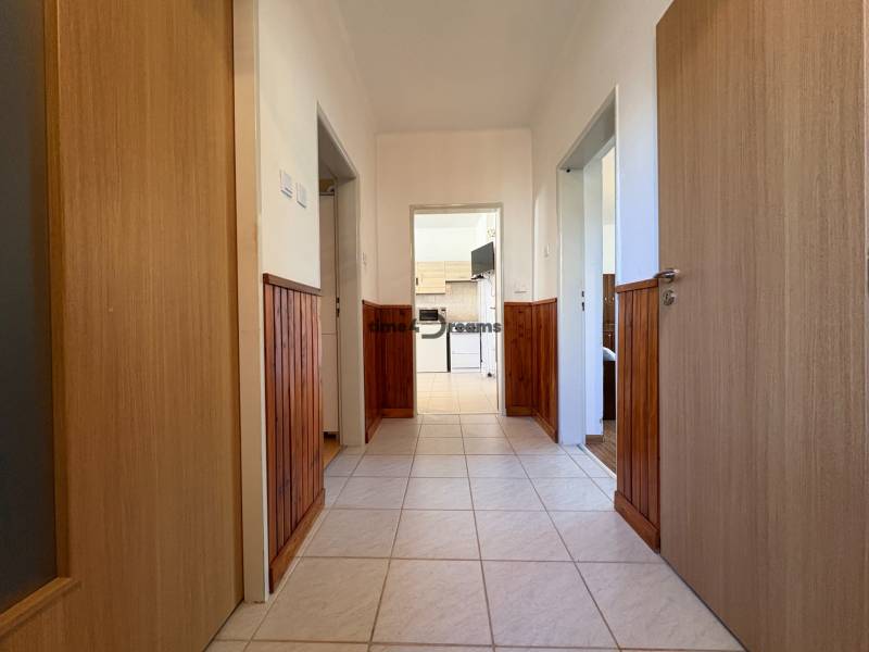 Na predaj: Rodinný dom v meste Levice - Chodba rodinného domu s keramickou dlažbou a paleťovanou drevenou stenou.