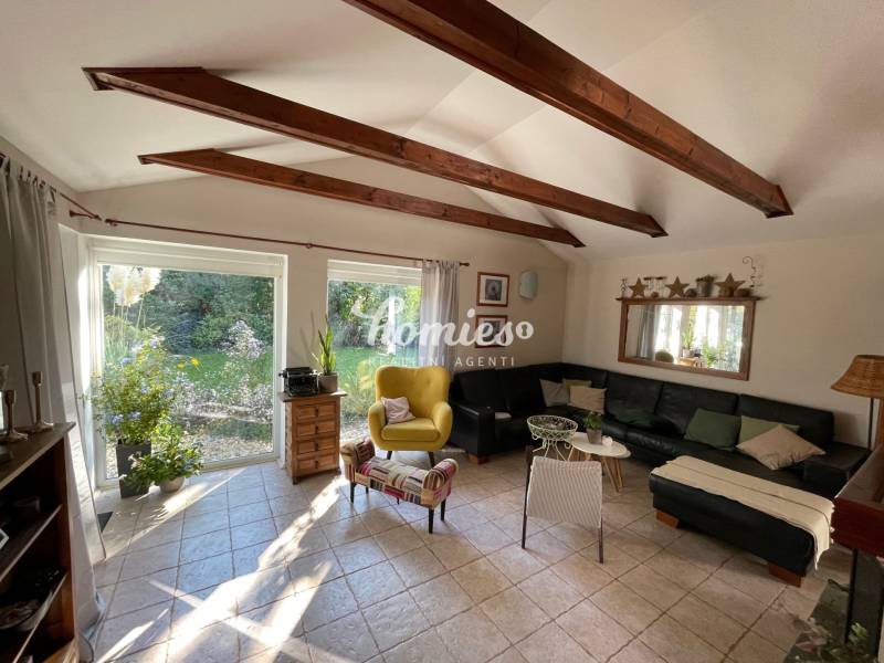 PREDAJ krásny 6 izb. rod. dom prepojený s prírodou - Obývačka v rodinnom dome s výhľadom do záhrady, trámový strop, čierna sedačka.