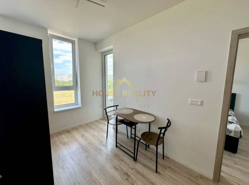 Nový 2 izbový byt SLNEČNICE, Labutia ulica, Bratislava V. Petržalka - Jedálenský kút v 2-izbovom byte s podlahou s dreveným dekorom a veľkými oknami.