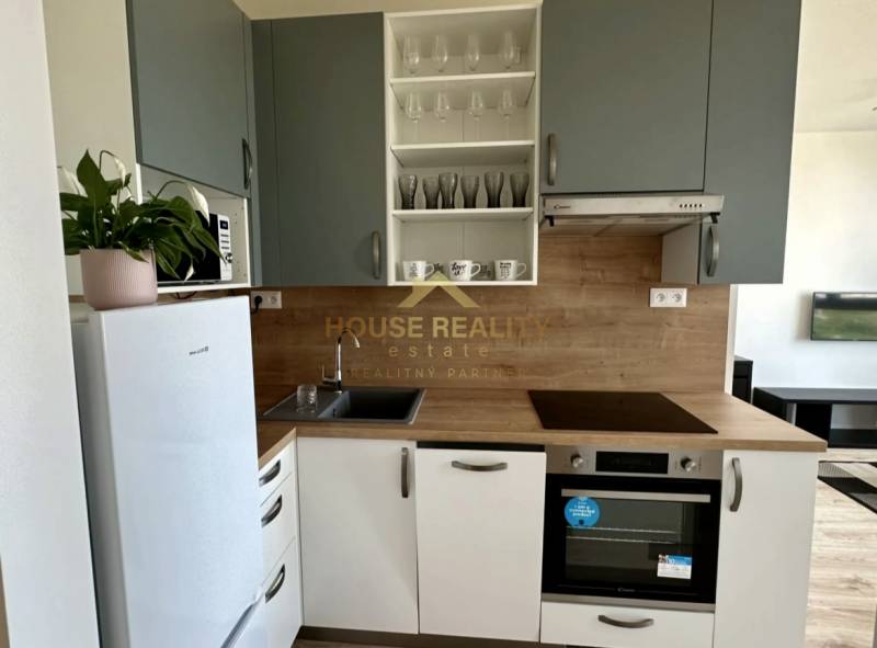 Nový 2 izbový byt SLNEČNICE, Labutia ulica, Bratislava V. Petržalka - Kuchyňa v 2-izbovom byte s bielou chladničkou a dreveným dekorom.