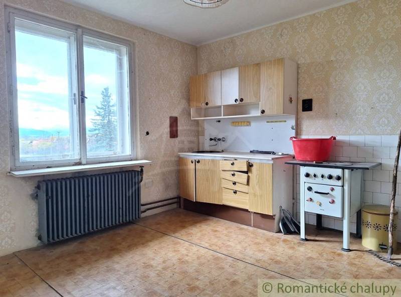 Dom v pôvodnom stave na krásnom pozemku (2130m2) v malej dedinke na Li - Kuchyňa v rodinnom dome s retro sporákom, podlahou s dreveným dekorom a výhľadom.