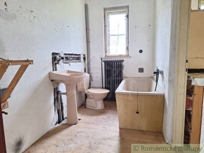 Dom v pôvodnom stave na krásnom pozemku (2130m2) v malej dedinke na Li - Kúpeľňa v rodinnom dome so sedacou vaňou, radiátorom a podlahou s dreveným dekorom.