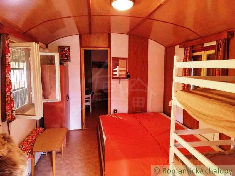 Chata nad kúpeľmi Dudince s vlastným pozemkom - Interiér chaty s poschodovou posteľou, podlahou s dreveným dekorom a otvoreným oknom.