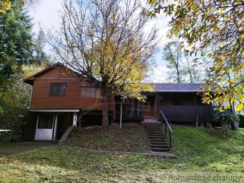 Chata nad kúpeľmi Dudince s vlastným pozemkom - Chata v Dudincoch obklopená stromami a sviežou zeleňou, ideálna na oddych.