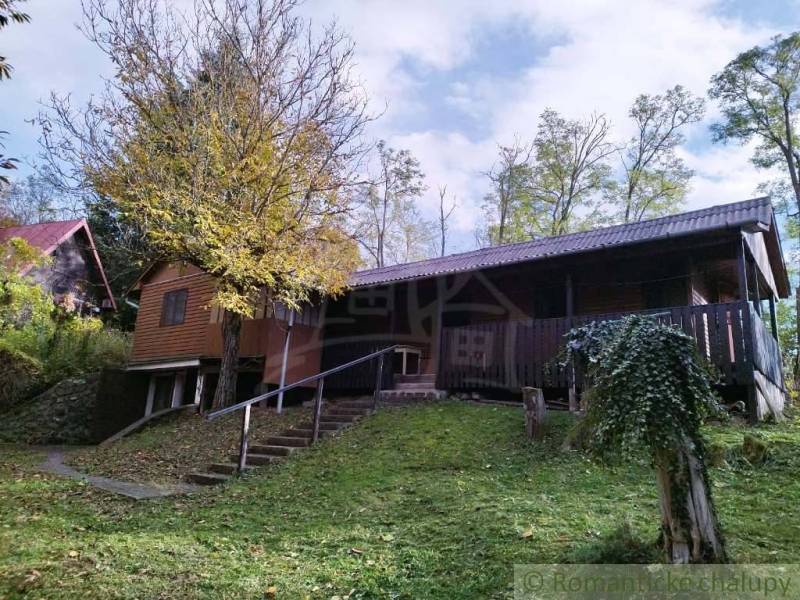 Chata nad kúpeľmi Dudince s vlastným pozemkom - Chata v Dudinciach obklopená prírodou s terasou a stromami na dvore.