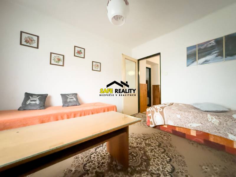 Rodinný dom s veľkým pozemkom v obci Sklené,  - Obývacia izba v rodinnom dome s kobercom a kresbami na stene.