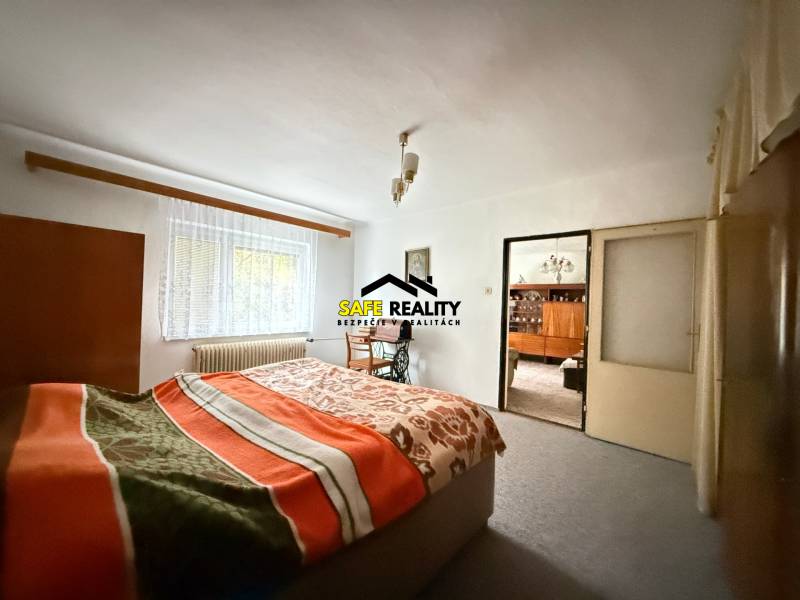 Rodinný dom s veľkým pozemkom v obci Sklené,  - Spálňa v rodinnom dome so svetlým kobercom, oknom a posteľou s dekou.