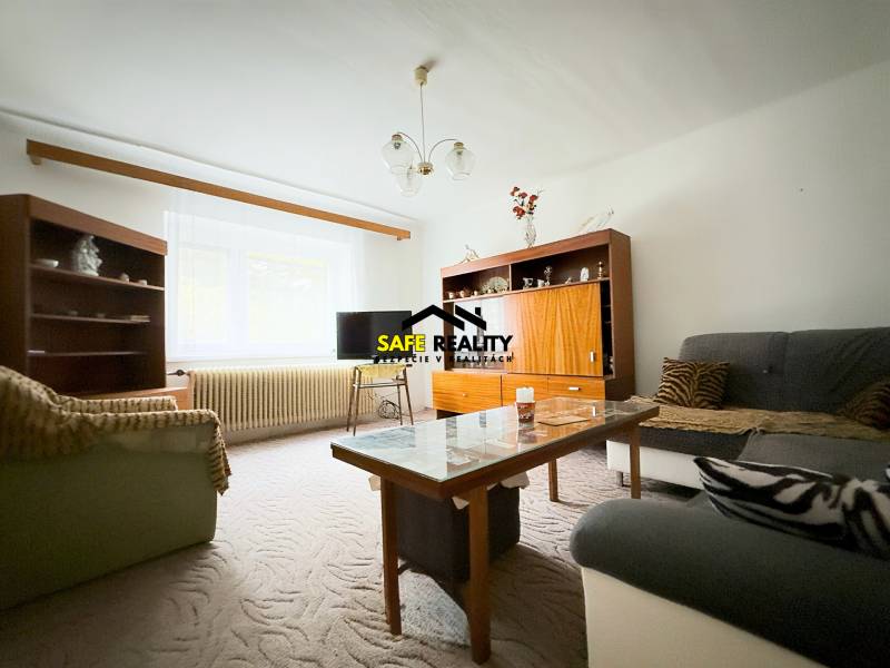 Rodinný dom s veľkým pozemkom v obci Sklené,  - Obývačka v rodinnom dome s pohovkami, skrinkami a stolíkom, kobercom na podlahe.