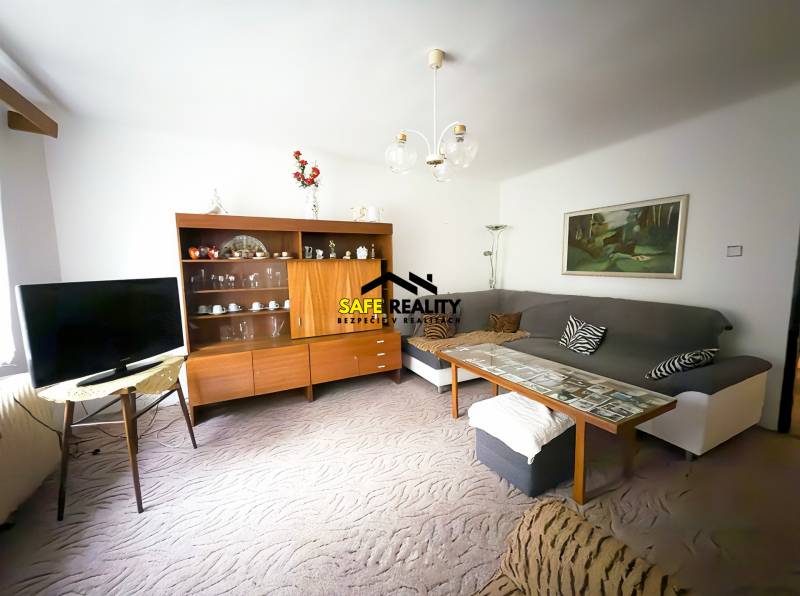 Rodinný dom s veľkým pozemkom v obci Sklené,  - Obývacia izba v rodinnom dome s pohovkou, televízorom a drevenou obývačkovou stenou.