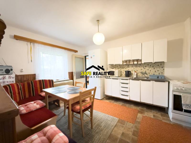 Rodinný dom s veľkým pozemkom v obci Sklené,  - Kuchyňa v rodinnom dome so svetlým nábytkom, jedálenským stolom a posedením.