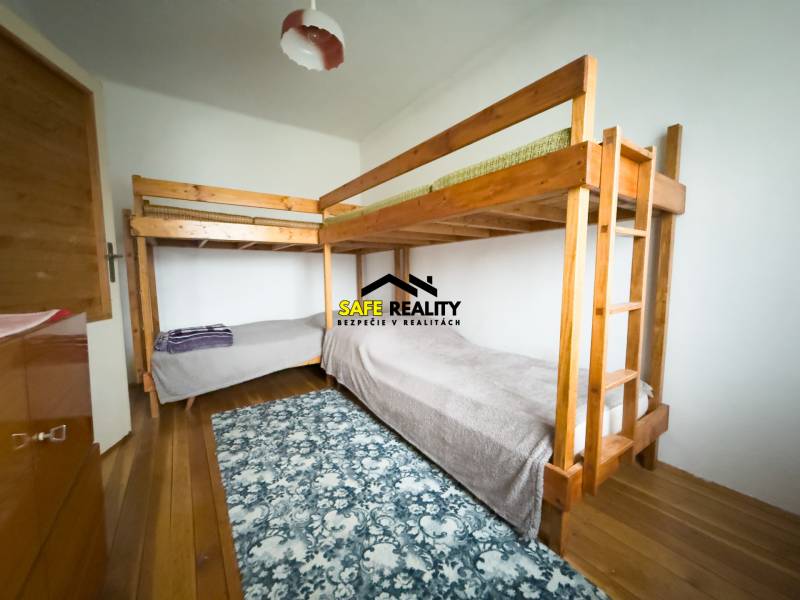 Rodinný dom s veľkým pozemkom v obci Sklené,  - Poschodová posteľ v rodinnom dome s podlahou s dreveným dekorom a vzorovaným kobercom.