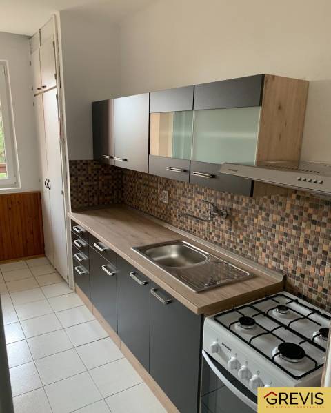 Priestranný 2-izbový byt (62 m²) s Lodžiou, Nobelova – Nové Mesto - Kuchyňa v 2-izbovom byte s mozaikovým obkladom a podlahou s dreveným dekorom.