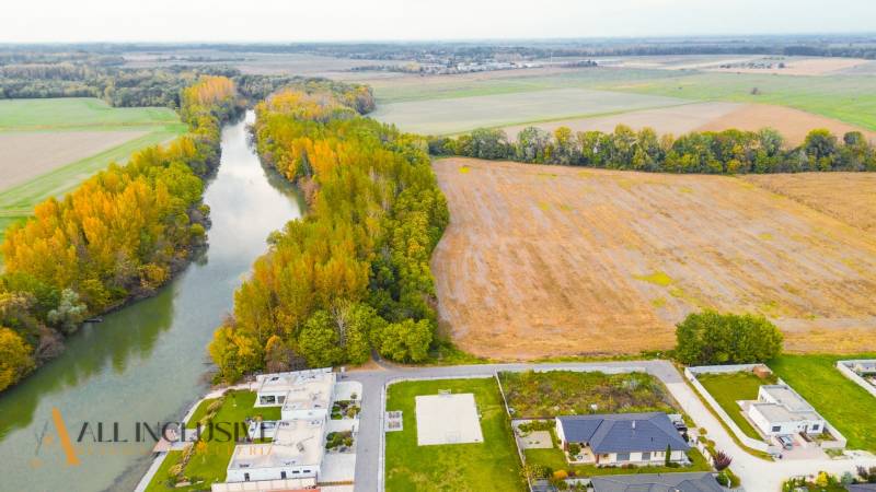 NA PREDAJ INVESTIČNÝ STAVEBNÝ POZEMOK, JAHODNÁ - Developerské pozemky v Jahodnej pri rieke, obklopené širými poľami a novými budovami.