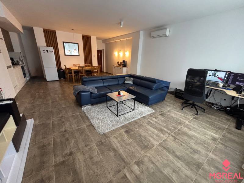 Veľký 96 m2  2 izbový byt s garážovým státím Topoľčany Centrum  - Obývacia izba v 2-izbovom byte s modrou sedačkou a pracovným stolom.