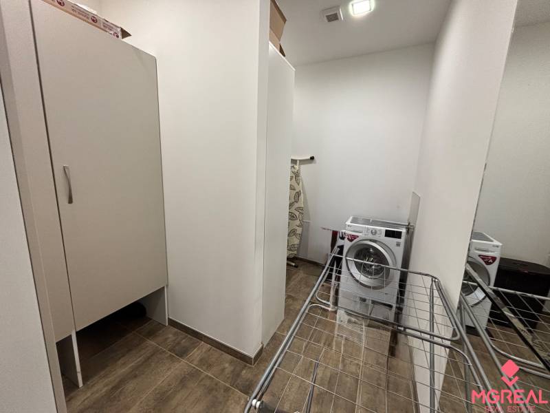 Veľký 96 m2  2 izbový byt s garážovým státím Topoľčany Centrum  - Výklenok s práčkou, sušiakom a skriňou v 2-izbovom byte; podlaha s dreveným dekorom.