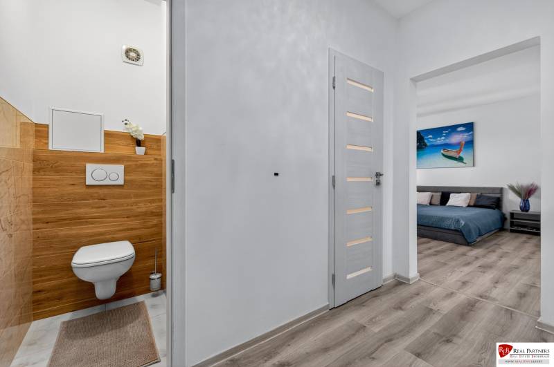 REZERVOVANÉ Predaj moderný 1-izbový byt, 45,24m2, Bratislava IV - Chodba v 1-izbovom byte s toaletou a podlahou s dreveným dekorom.