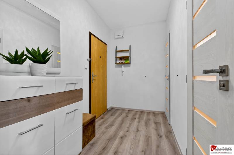 REZERVOVANÉ Predaj moderný 1-izbový byt, 45,24m2, Bratislava IV - Vstupná chodba v 1-izbovom byte s podlahou s dreveným dekorom a bielym nábytkom.