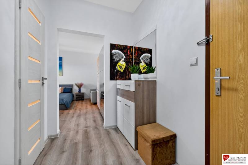 REZERVOVANÉ Predaj moderný 1-izbový byt, 45,24m2, Bratislava IV - Chodba v 1-izbovom byte s podlahou s dreveným dekorom a dekoráciou na stene.
