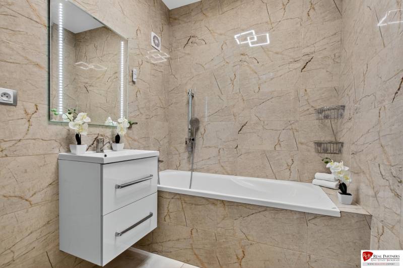 REZERVOVANÉ Predaj moderný 1-izbový byt, 45,24m2, Bratislava IV - Kúpeľňa v 1-izbovom byte so svetlými obkladmi, umývadlom a vaňou.