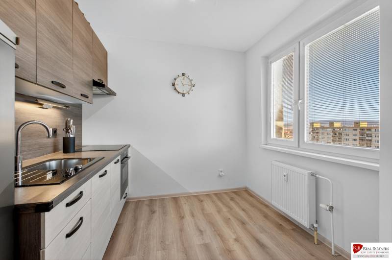 REZERVOVANÉ Predaj moderný 1-izbový byt, 45,24m2, Bratislava IV - Kuchyňa v 1-izbovom byte s podlahou s dreveným dekorom a bielymi stenami.