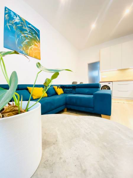 NA PRENÁJOM ŠTÝLOVÝ 2-IZBOVÝ BYT V CENTRE KOŠÍC, DREVNÝ TRH - Obývacia izba v 2-izbovom byte so sedačkou a abstraktným obrazom na stene.