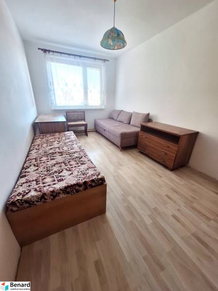 REZERVOVANÝ 2,5 IZBOVÝ BYT, 65 M2,PREŠOV,UL. FEDERÁTOV - Izba v 3-izbovom byte s podlahou s dreveným dekorom, kreslom a posteľou.