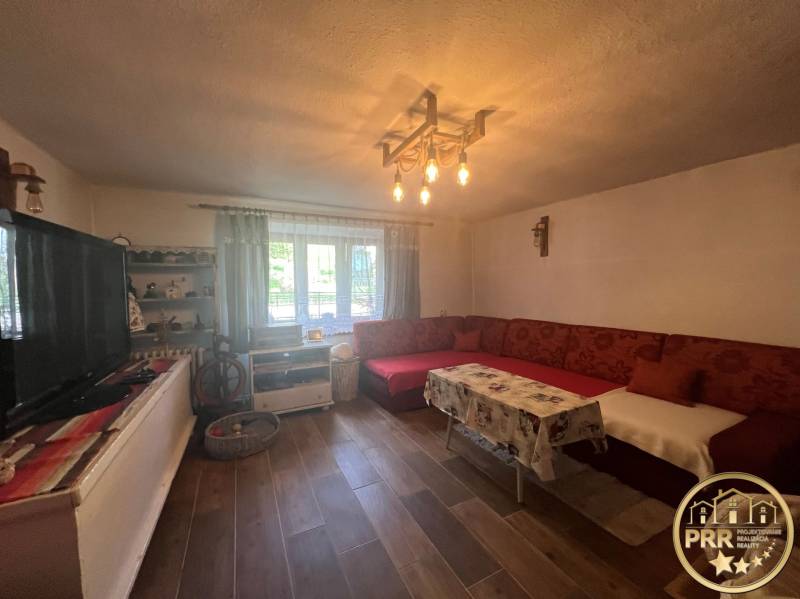 !! NOVÁ CENA !! predaj romantickej chalúpky v Šípkove  - Obývacia izba a chata s tradičným nábytkom, pohovkou a drevenou podlahou pre relax.