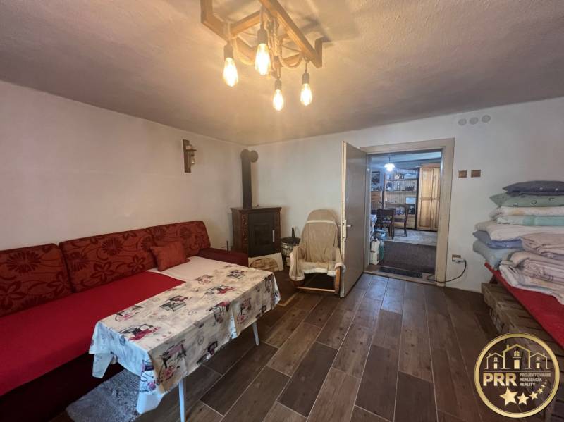 !! NOVÁ CENA !! predaj romantickej chalúpky v Šípkove  - Pohodlná izba v chate s útulným sedením, krbom a dreveným stropom.