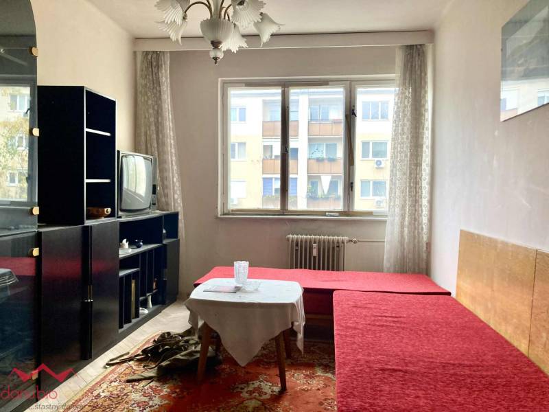 3-izbový byt s loggiou v širšom centre, Komárno - Obývačka v 3-izbovom byte s červenou pohovkou, koberec, starší televízor, presvetlený priestor.