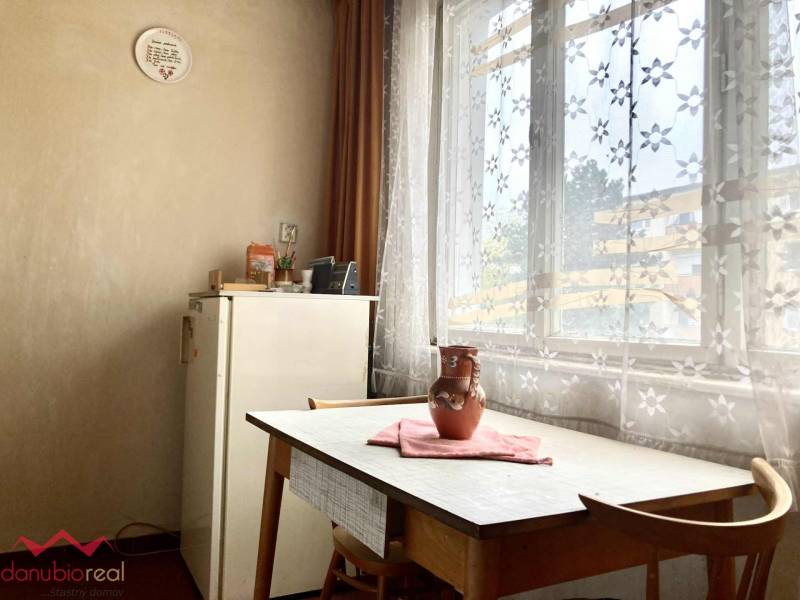 3-izbový byt s loggiou v širšom centre, Komárno - Jedáleň v 3-izbovom byte so stolom, stoličkami a záclonami s kvetinovým vzorom.