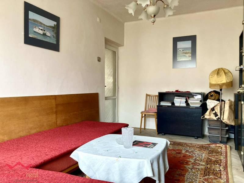 3-izbový byt s loggiou v širšom centre, Komárno - Obývacia izba v 3-izbovom byte s pohovkou, kobercom a dekoračnými obrázkami na stene.