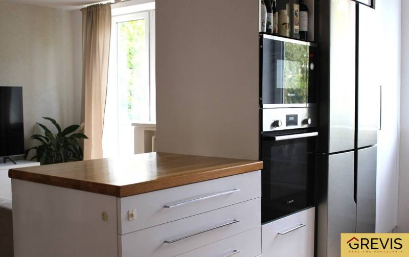 Elegantný 3 izbový byt (78 m²) s 2 balkónmi po kompletnej rekonštrukci - Kuchyňa v 3-izbovom byte, tmavá skrinka so vstavanou rúrou, vedľa chladnička.