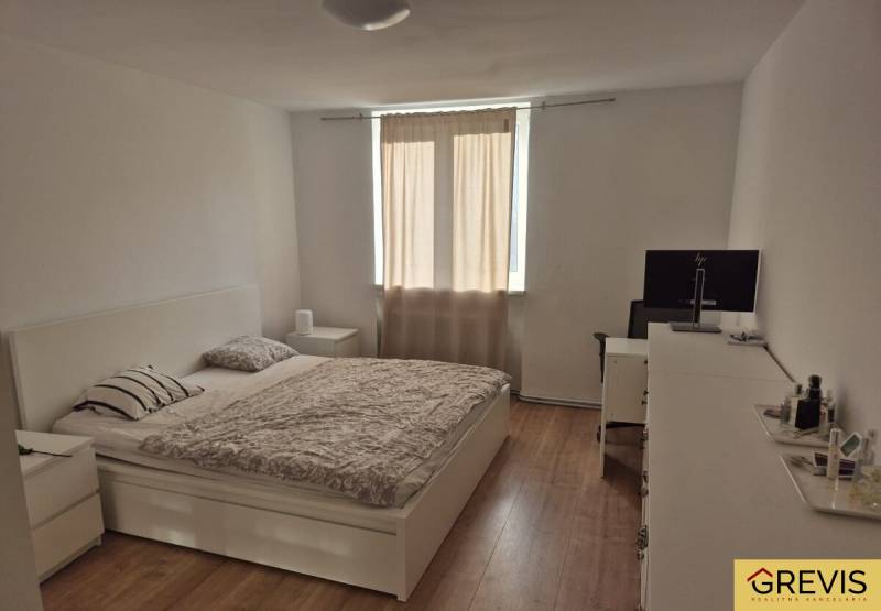 Elegantný 3 izbový byt (78 m²) s 2 balkónmi po kompletnej rekonštrukci - Svetlá spálňa v 3-izbovom byte s posteľou a podlahou s dreveným dekorom.