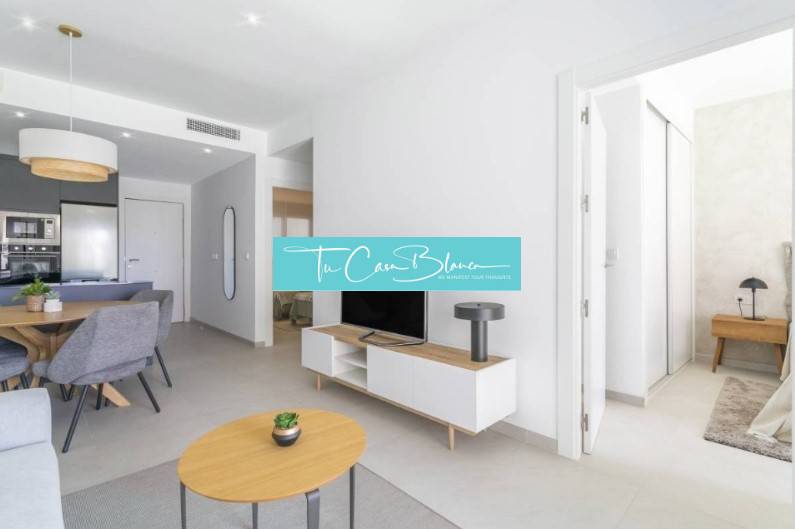 Novostavba Apartmán La Mata, 78m2, bazén, garáž - Rekreačný apartmán s otvorenou obývacou izbou, jedálenským stolom a podlahou s dreveným dekorom.