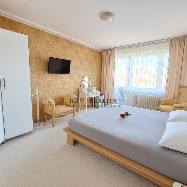 HD reality, predaj 3 izbového bytu na Medvedzí v meste Tvrdošín. - Spálňa v 3-izbovom byte s elegantným nábytkom, zlatou tapetou a bielym kobercom.