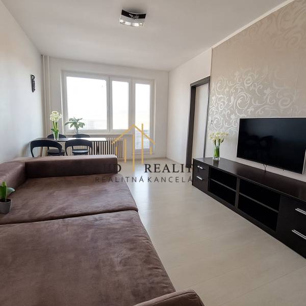 HD reality, predaj 3 izbového bytu na Medvedzí v meste Tvrdošín. - Obývačka v 3-izbovom byte s veľkou sedačkou, TV a podlahou s dreveným dekorom.