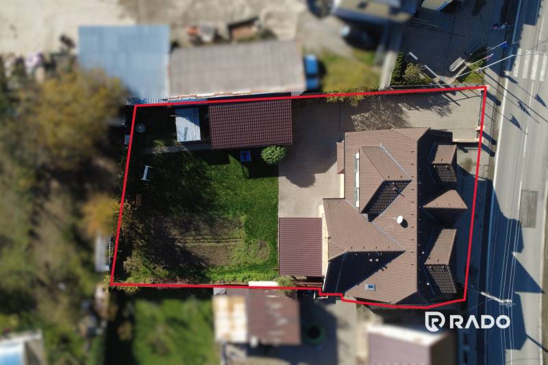 RADO| Podnikajte a zároveň bývajte pod jednou strechou! - Letecká snímka rodinného domu v obci Bolešov obklopeného záhradou a príjazdovou cestou.