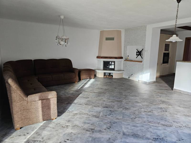 REZERVOVANÉ! Predáme 5-izbový rodinný dom na Štúrovej ulici, Vráble - Obývacia izba v rodinnom dome s podlahou s dreveným dekorom a rohovou pohovkou.