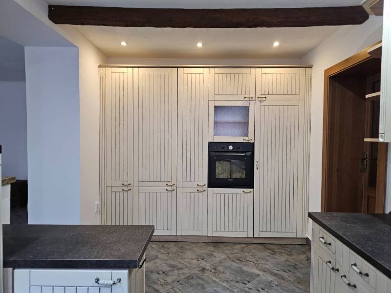 REZERVOVANÉ! Predáme 5-izbový rodinný dom na Štúrovej ulici, Vráble - Kuchyňa s tmavou pracovnou doskou a zabudovanou rúrou, podlaha s dreveným dekorom.